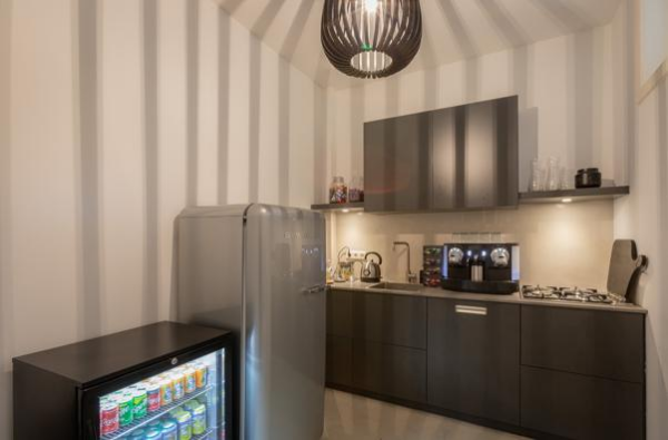 Moderne kitchenette aan de Van Baerlestraat met koelkast vol frisdrank, koffiezetapparaat en gasfornuis.